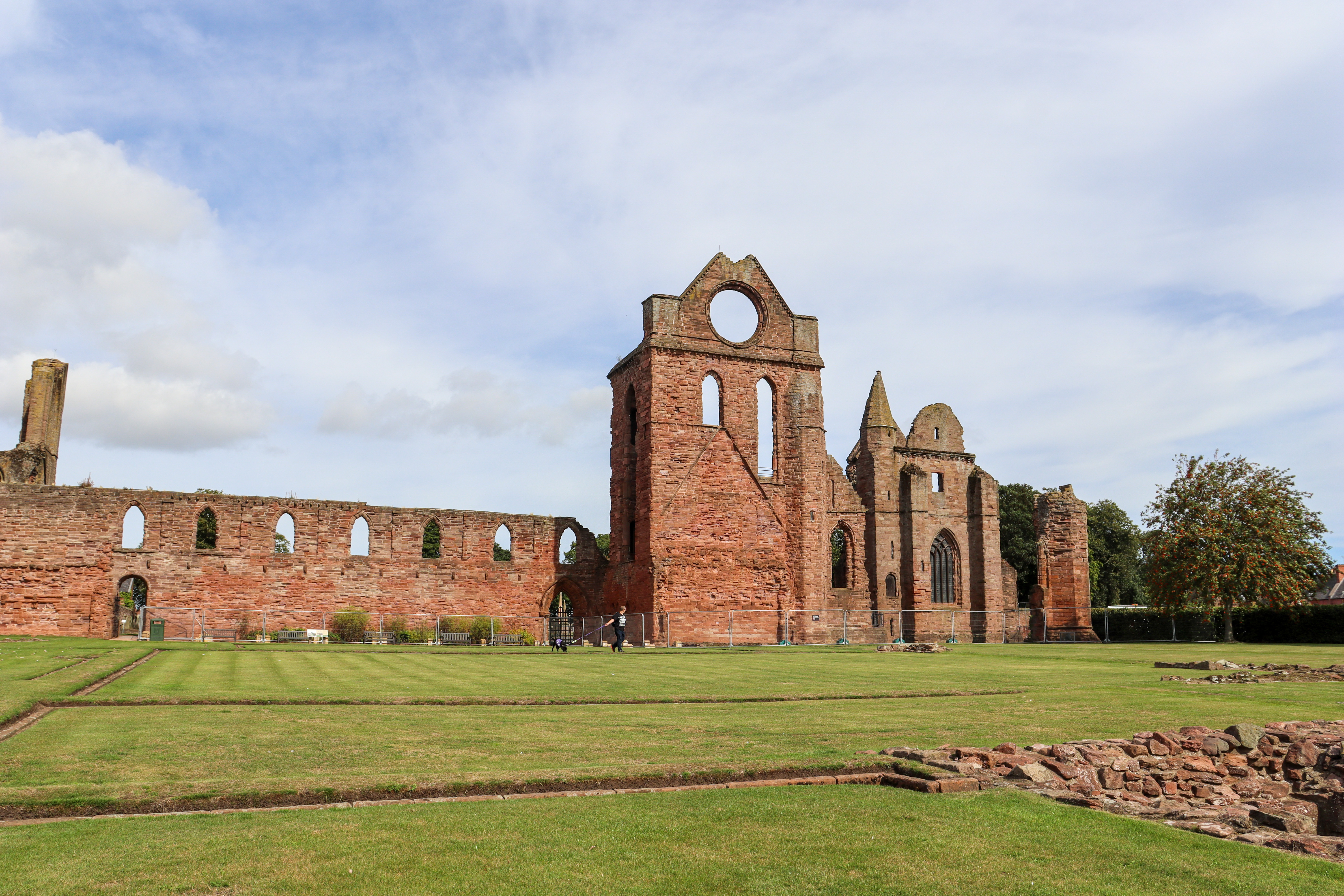 Ancient stone ruins of the side of an abbey building with extensive lawns in front