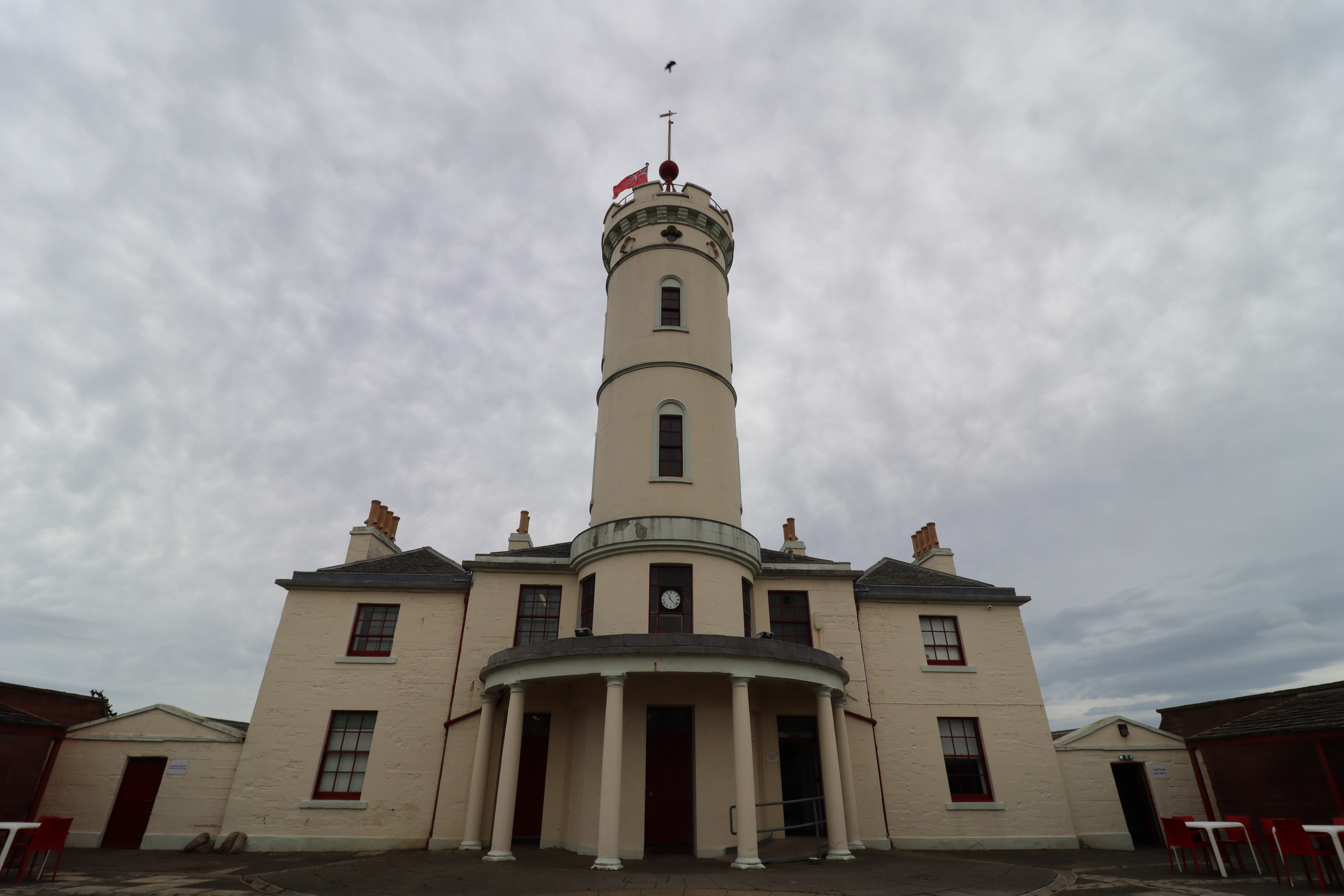 Symmetrical white building with a tower in the centre and four pillars around the entrance