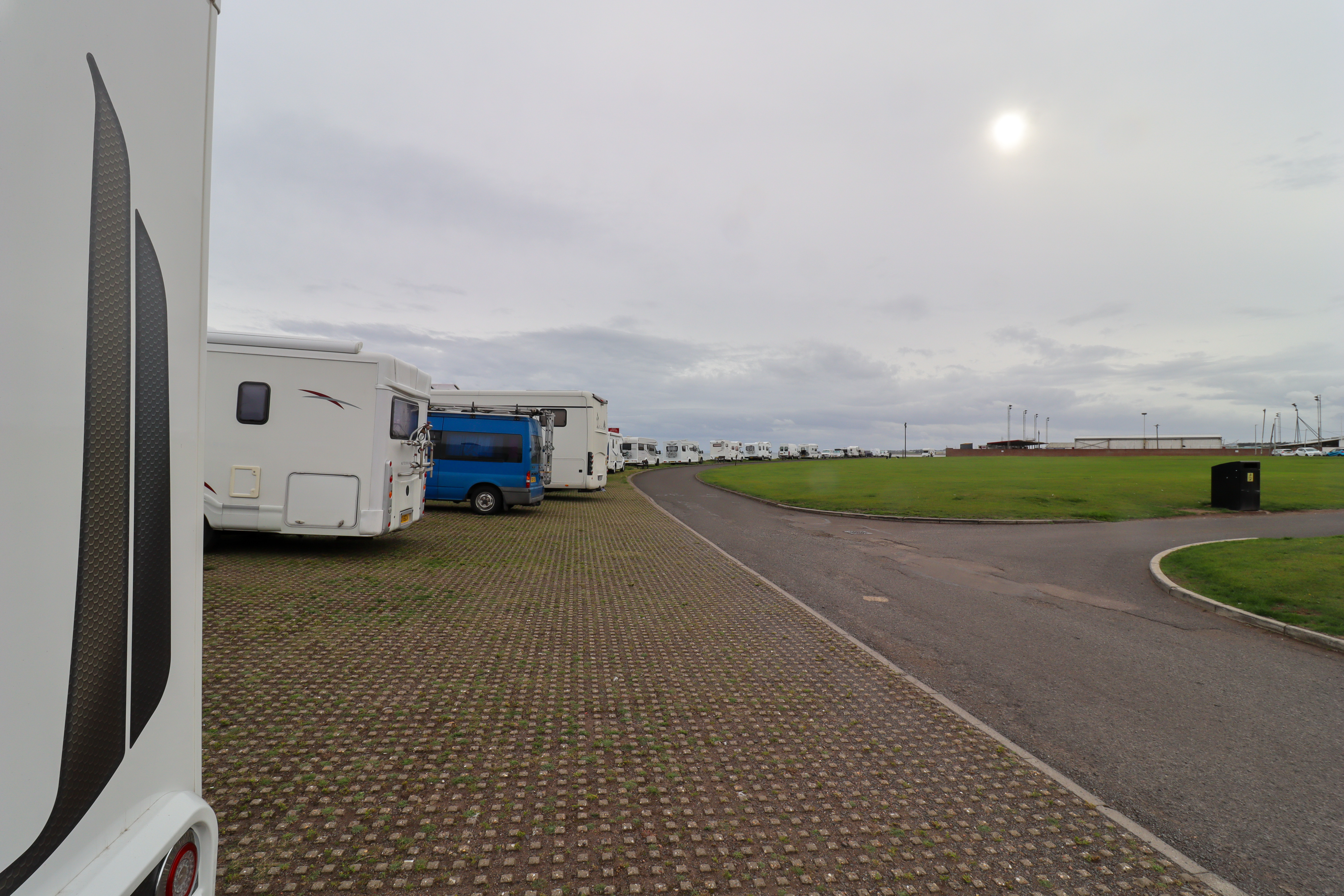 A long line of motorhomes parked along the sea wall.