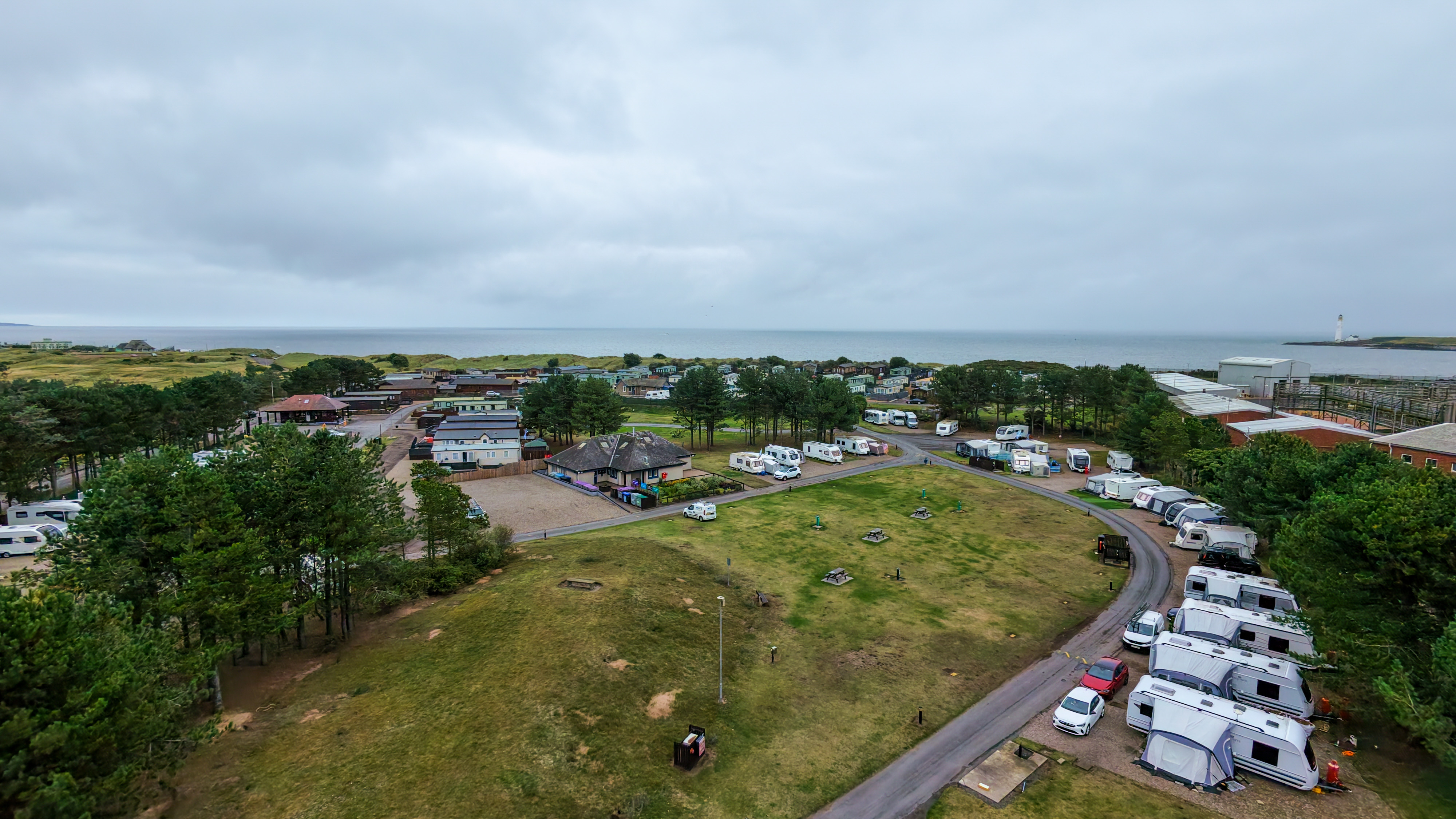 Aerial view of a caravan site with a variety of caravans and statics, and the sea behind.
