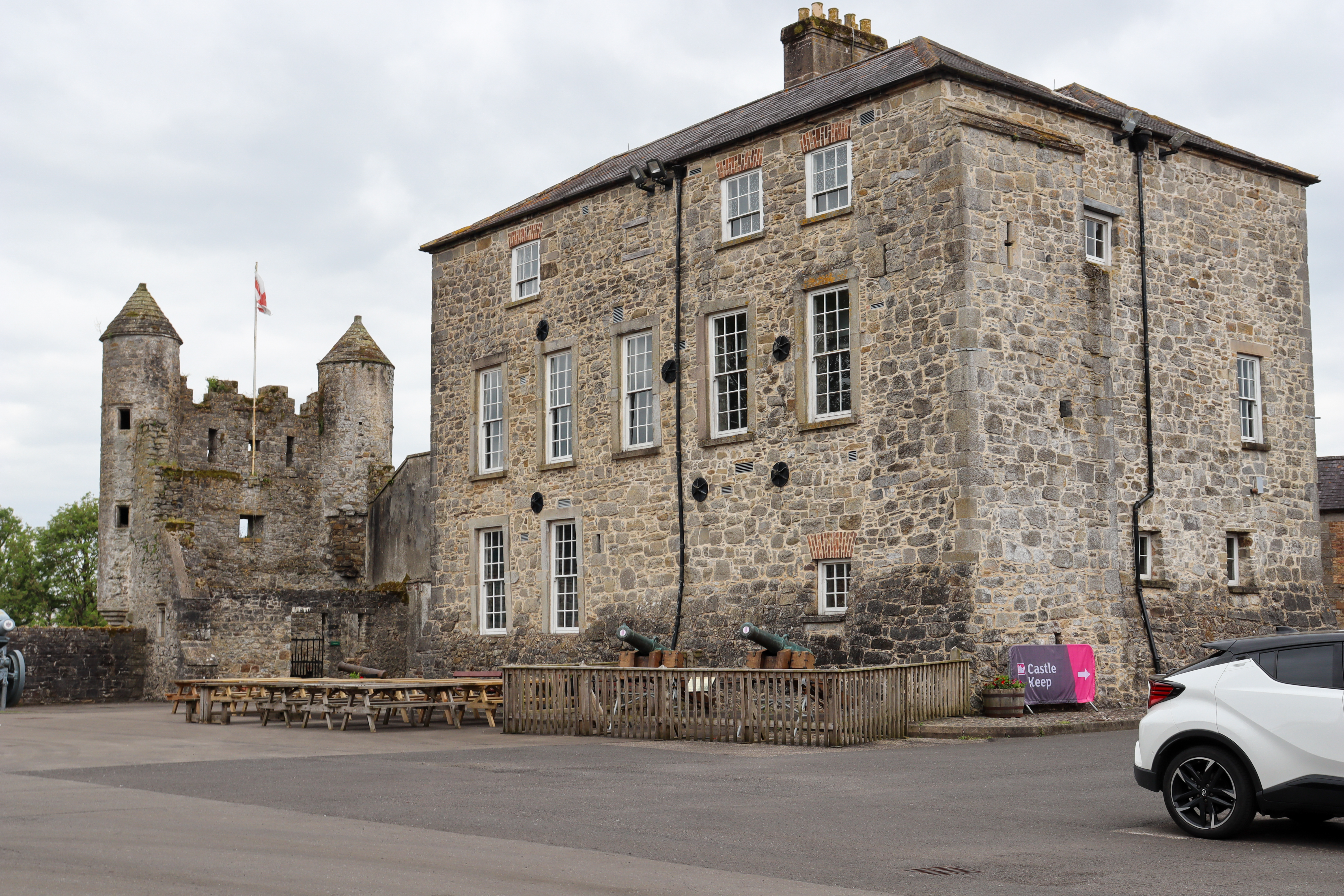 Old ruined castle keep with a large stone building next to it.