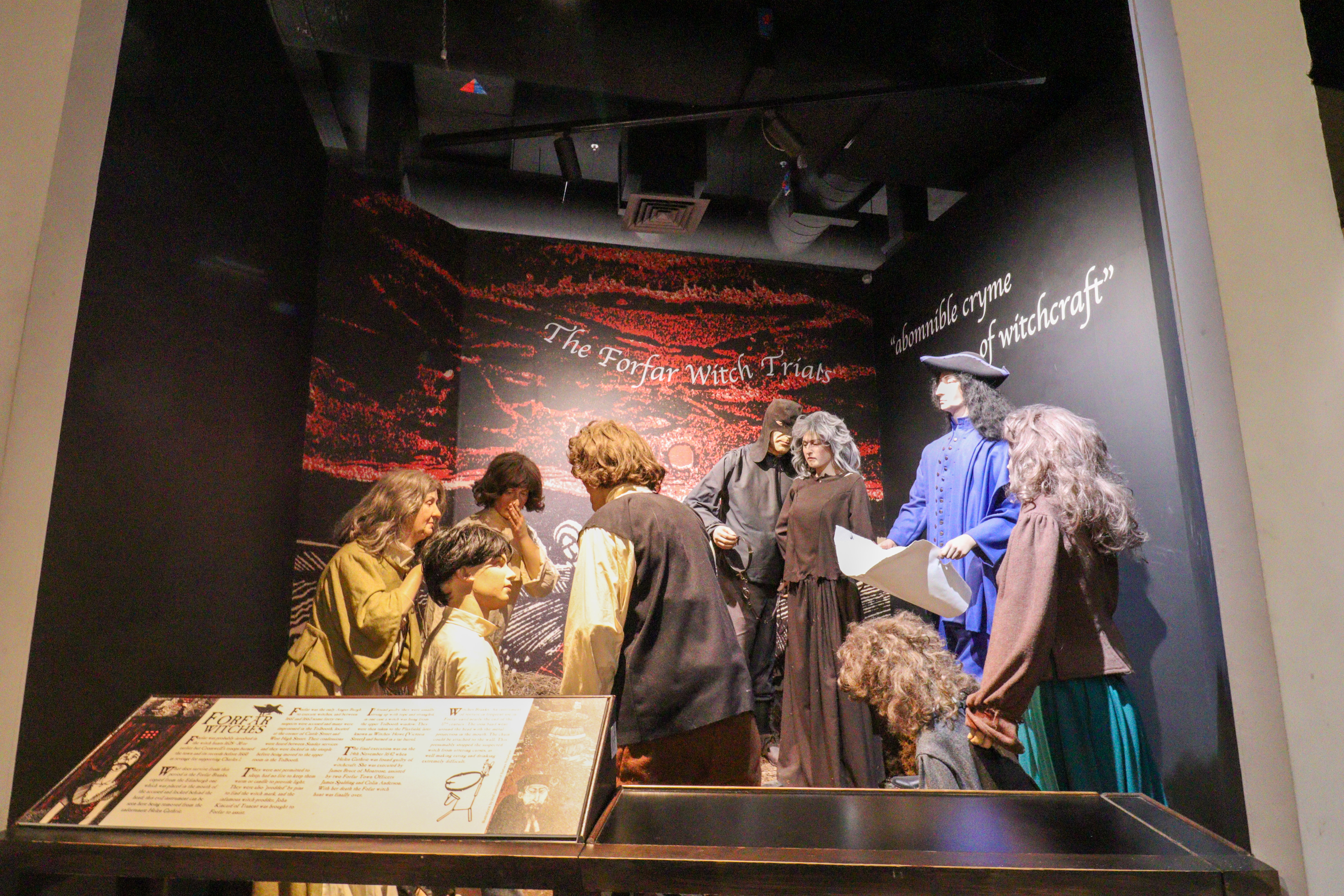 Scene showing a crowd shouting at a lady who has been branded a witch