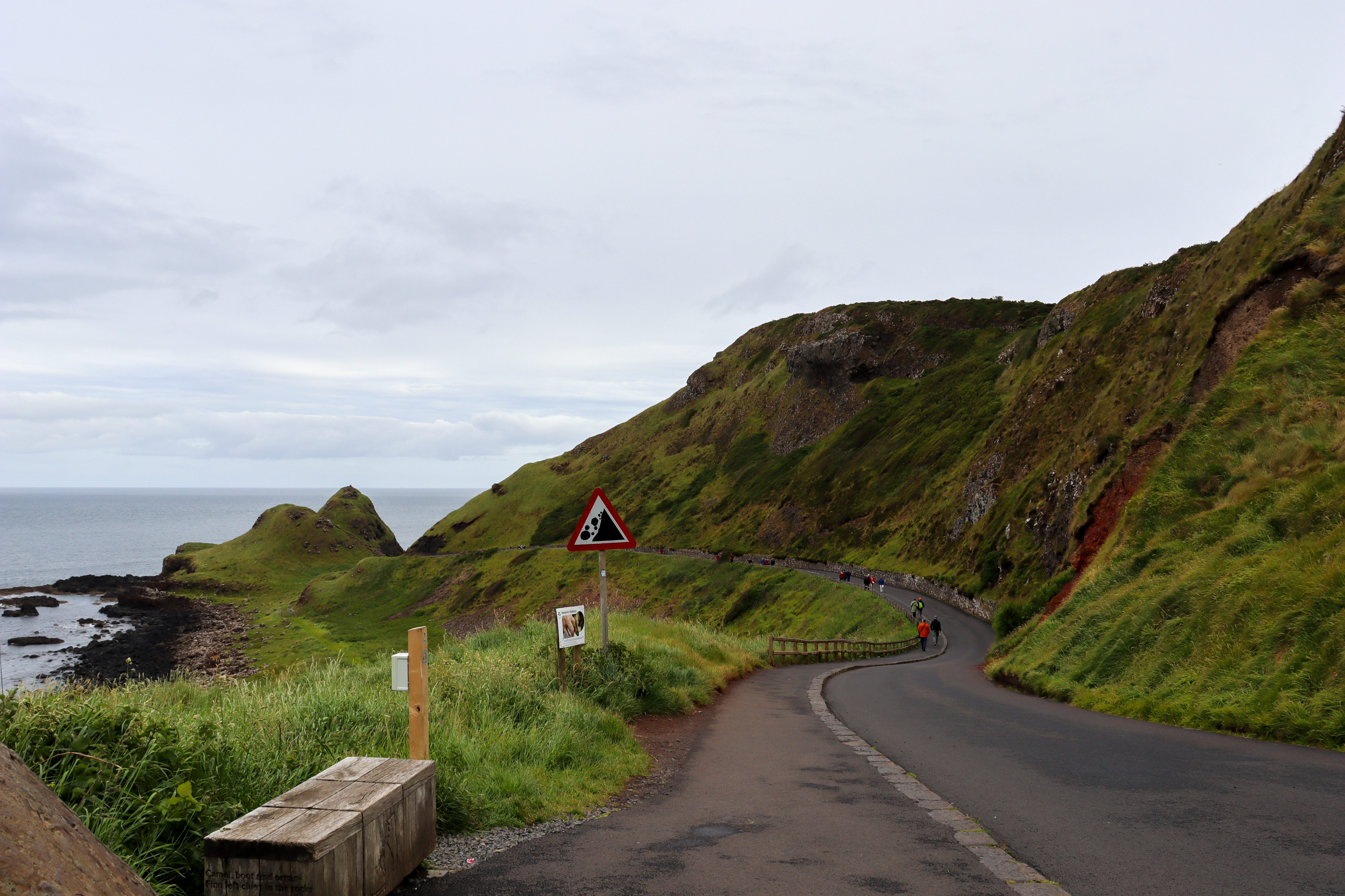 Good quality road and pavement leading down to the shore with cliffs on the right.