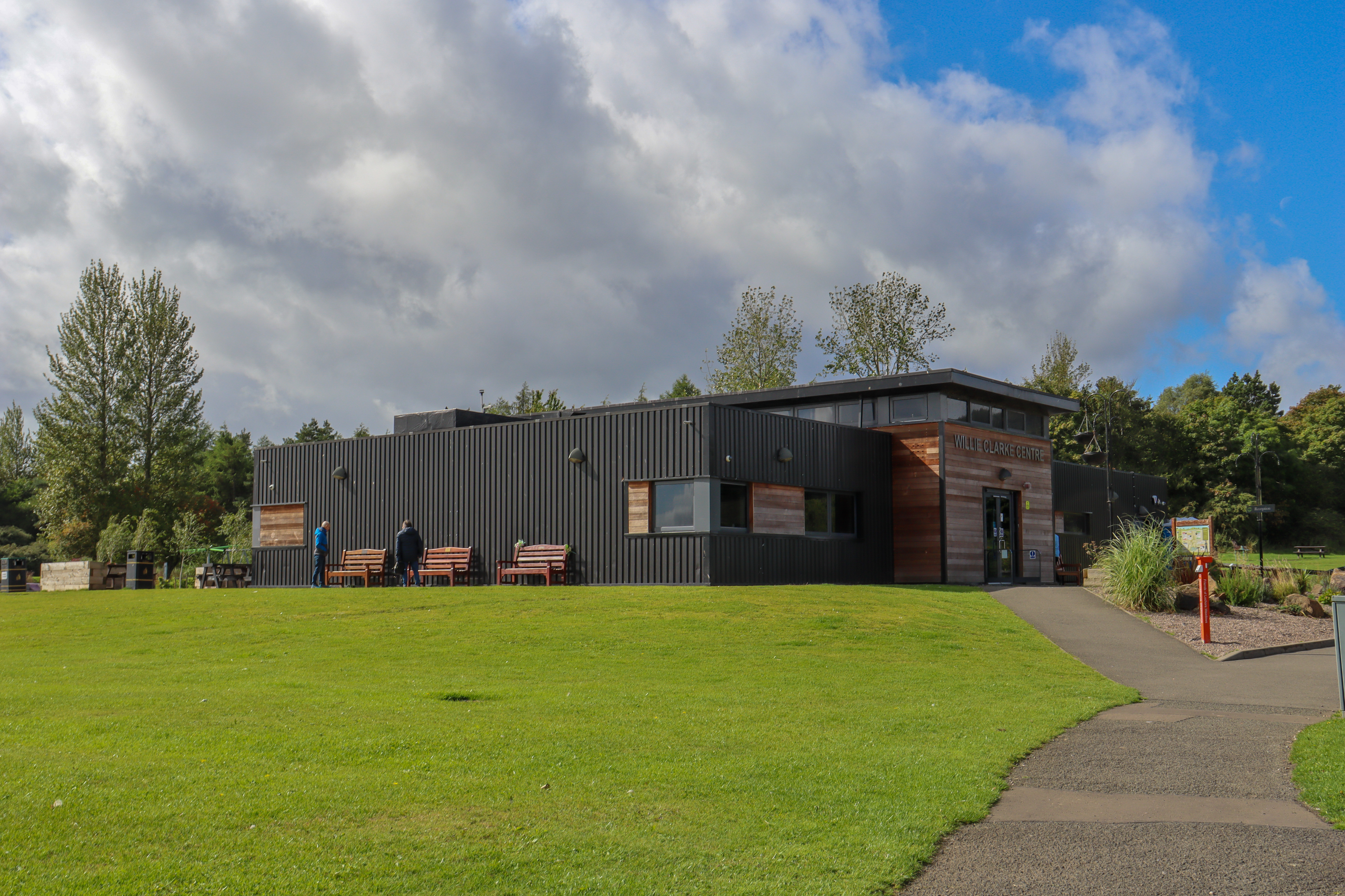 Wooden visitor centre with lawns and landscaped paths around it.