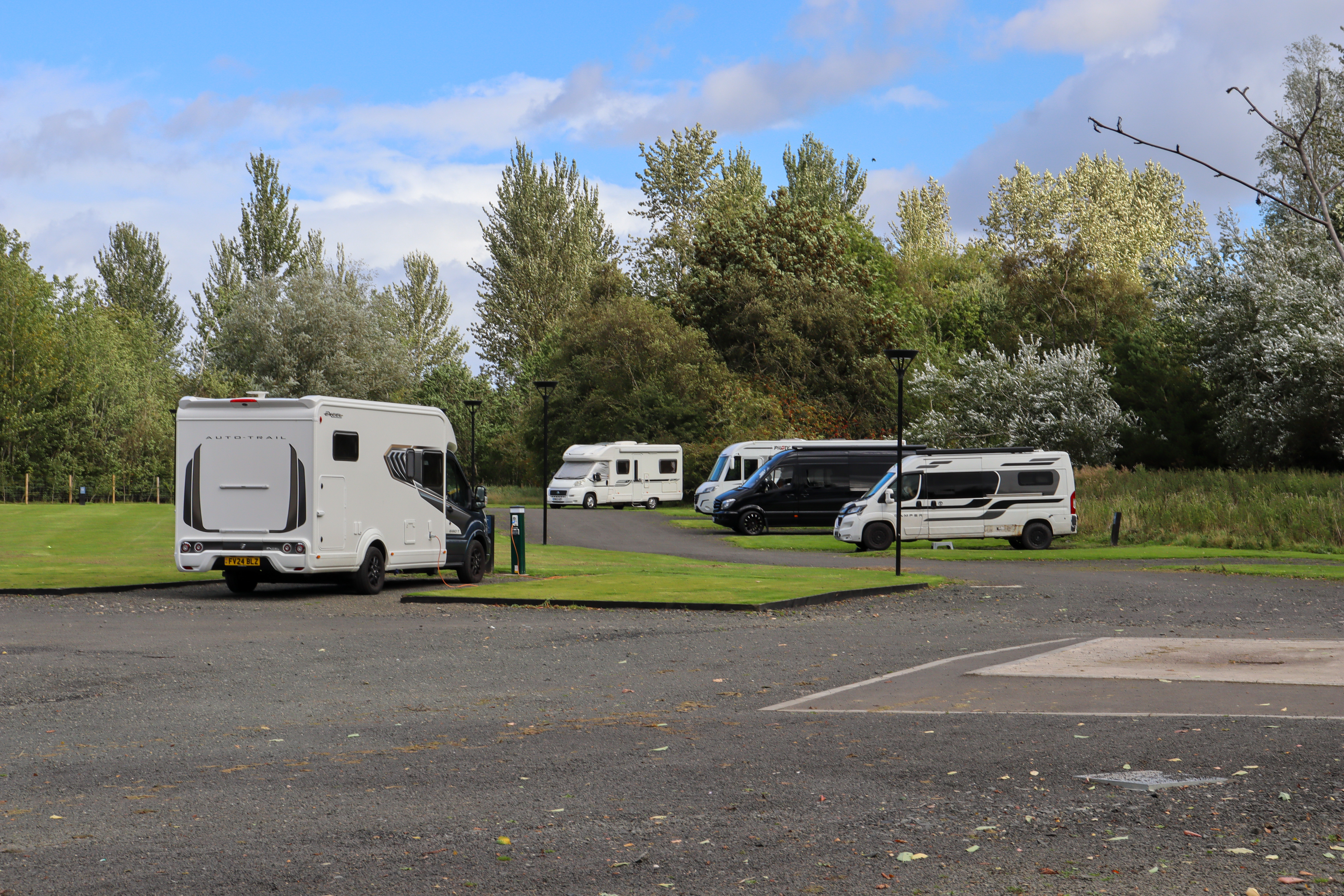 Four motorhomes pitched on a tidy site with gravel pitches with grass between.