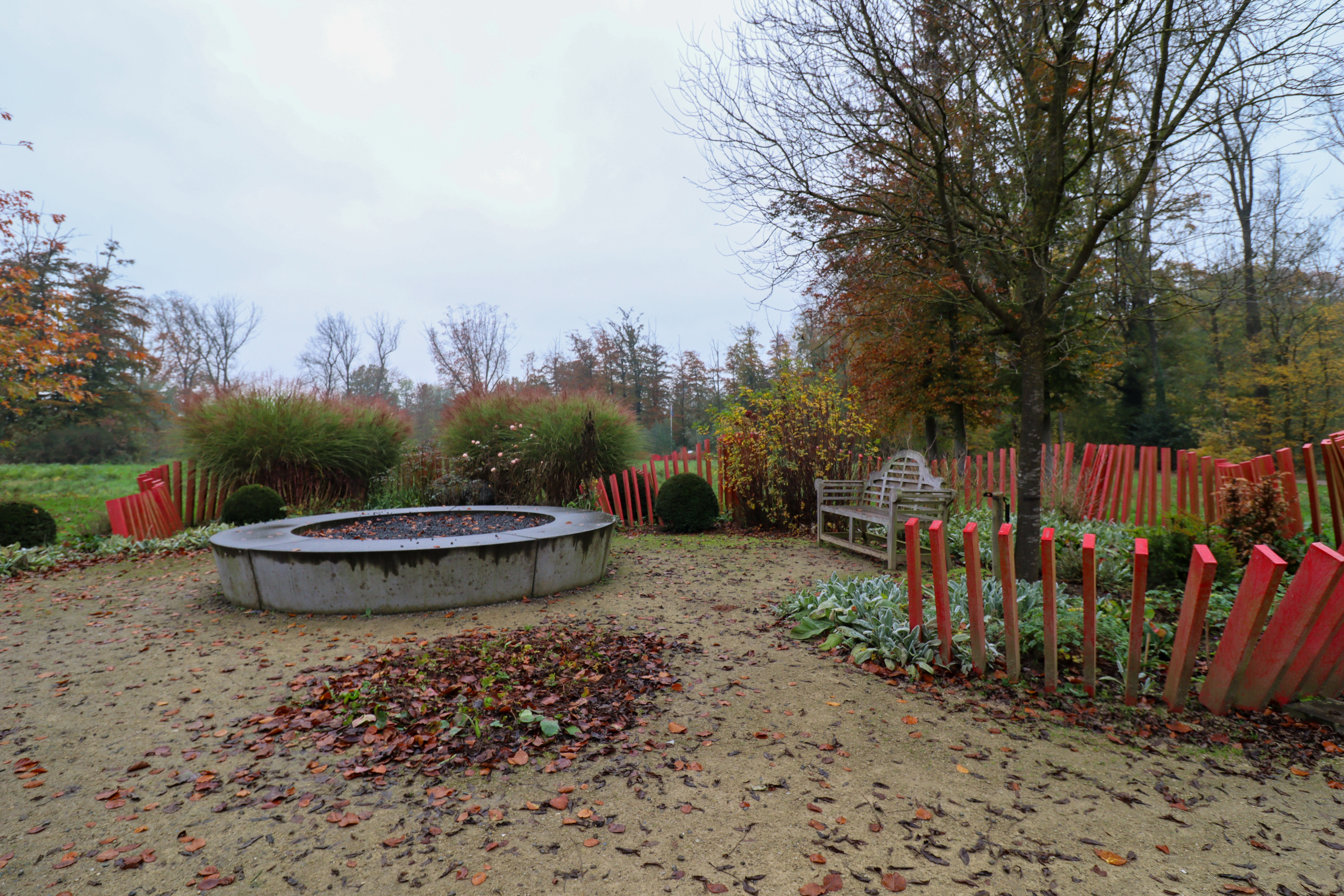 Winter garden with a stone circular raised bed in the middle and shrubs at the edges