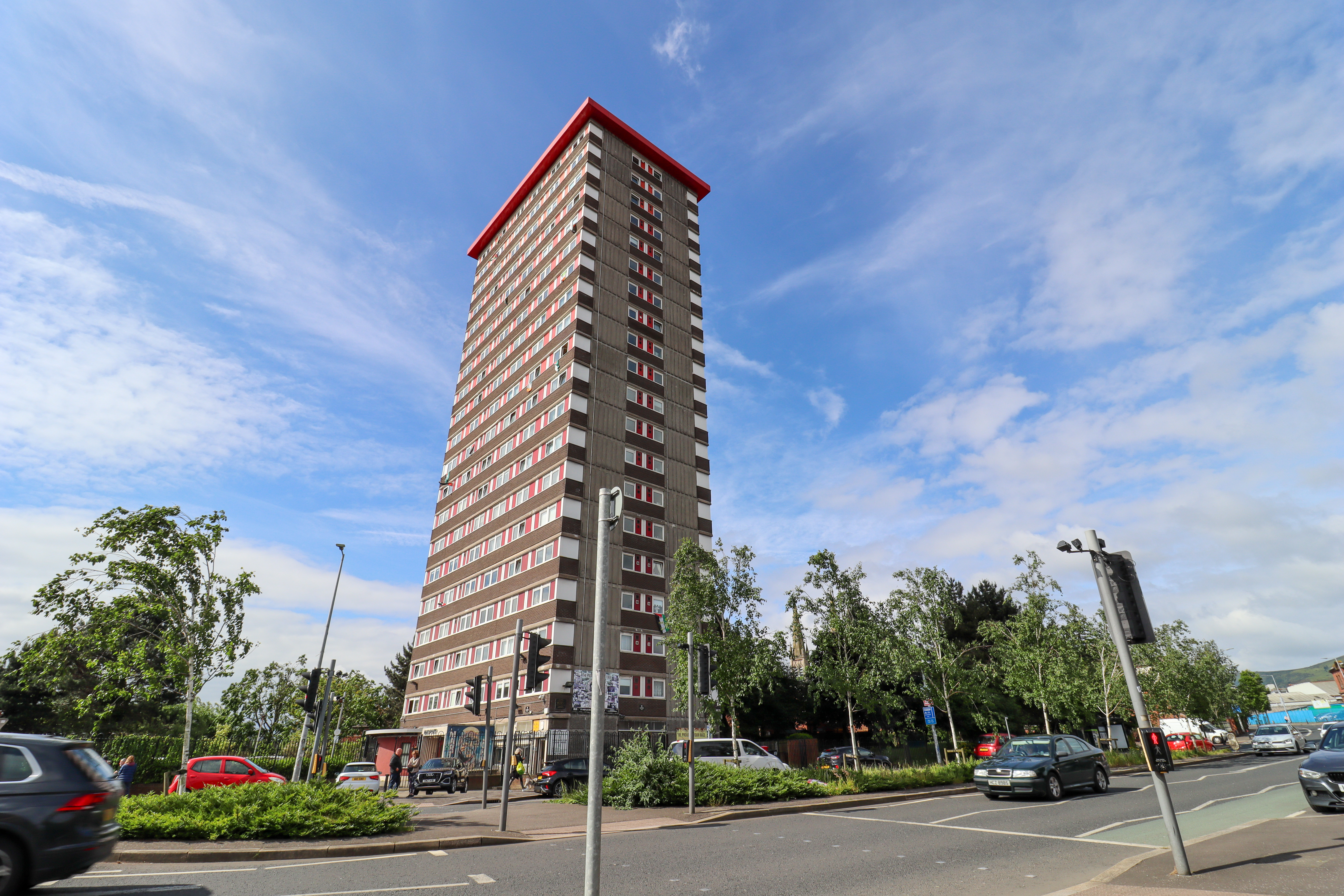 Large tower block next to a busy road.